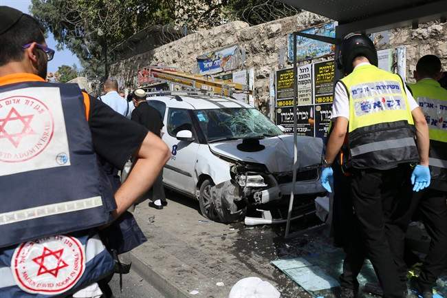 Police and emergency services respond to an attack in Jerusalem Tuesday, Oct. 13, 2015. A Palestinian rammed a vehicle into a bus stop then got out and started stabbing people killing one and wounding several others before he was shot dead, police said.