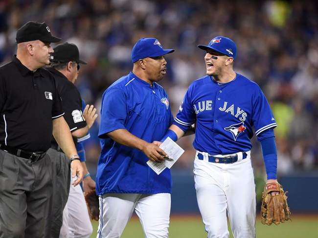 Toronto Blue Jays shortstop Troy Tulowitzki, right, is held back by bench coach DeMarlo Hale after being tossed from the game during eighth inning game three American League Championship Series baseball action against the Kansas City Royals in Toronto on Monday, Oct. 19, 2015. 