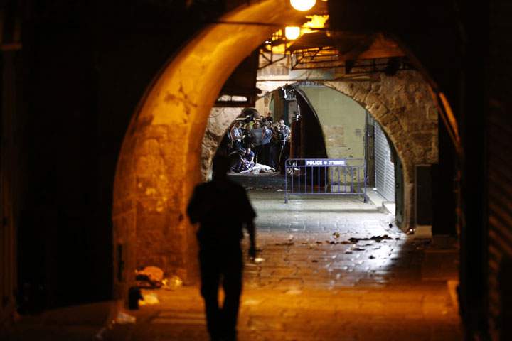 Israeli security forces and emergency services stand next to the body of a Palestinian who carried out a stabbing attack in the old city of Jerusalem on October 3, 2015. 