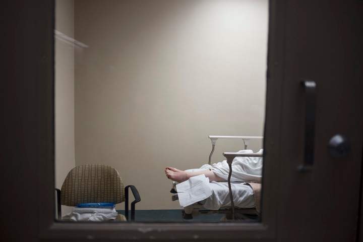 A patient’s feet are seen through a hospital room door in the emergency department of the Toronto East General Hospital