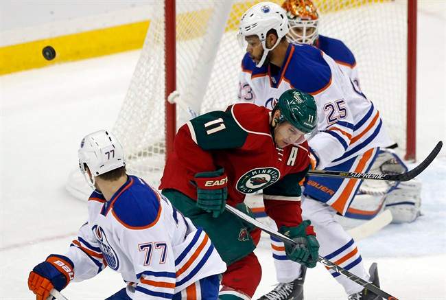 A shot goes high and wide past Minnesota Wild’s Zach Parise (11) as Edmonton Oilers' Darnell Nurse (25) defends in the first period of an NHL hockey game, Tuesday, Oct. 27, 2015, in St. Paul, Minn.