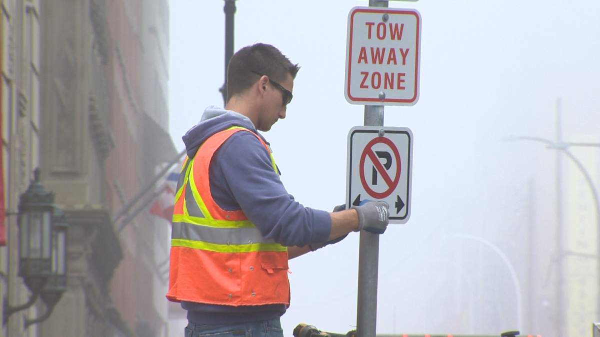 A city worker installs a "No Parking" sign on the Hollis Street bike lane. 