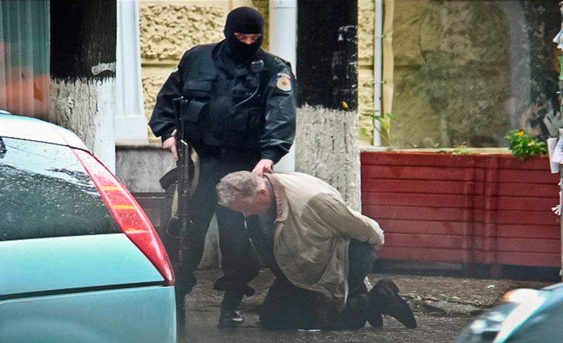 In this June 27, 2011 photo provided by the Moldova General Police Inspectorate, Teodor Chetrus is detained by a police officer in Chisinau, Moldova during a uranium-235 sting operation. (Moldova Police via AP)