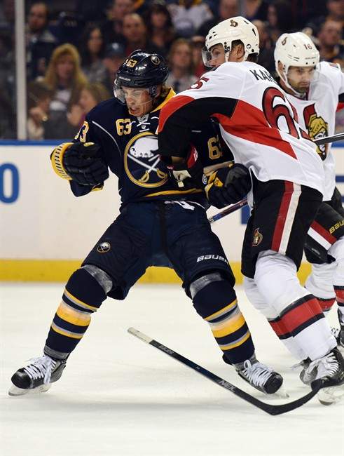 Buffalo Sabres center Tyler Ennis (63) is checked by Ottawa Senators defenseman Erik Karlsson (65) during the first period.