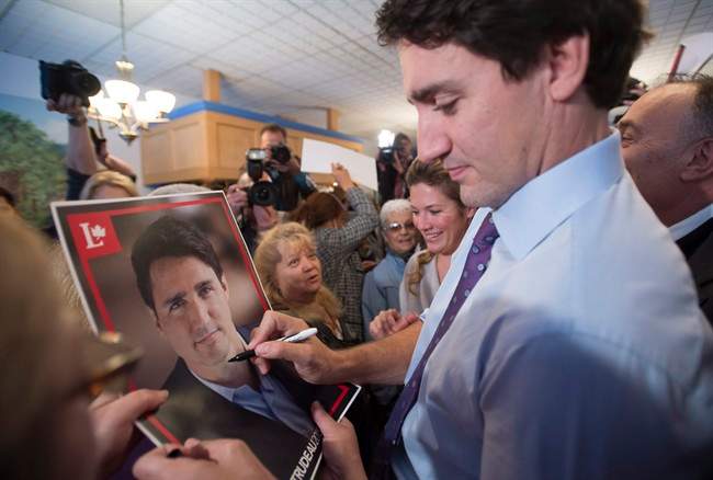 Liberal Leader Justin Trudeau signs a poster for a supporter during a campaign stop at a Greek restaurant, Thursday, October 15, 2015 in Laval, Que.