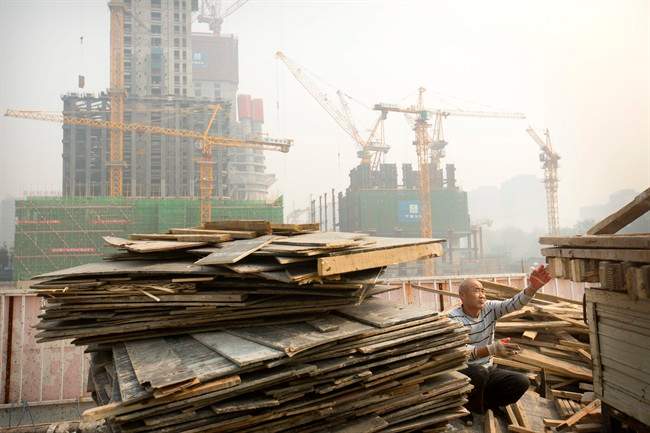 A worker tosses boards onto the back of a truck at a construction site in Beijing. 