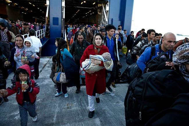 Migrants and refugees disembark from a ferry after their arrival from the northeastern Greek islands of Lesbos and Chios at the Athens' port of Piraeus, Sunday Oct. 25, 2015.