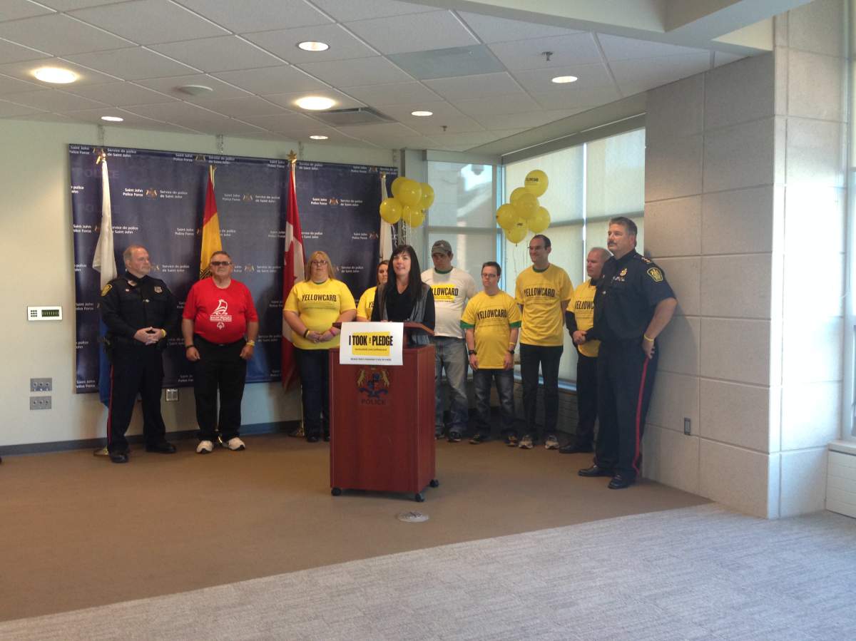 Police officers, along with members of NB Special Olympics take the Yellowcard Pledge.