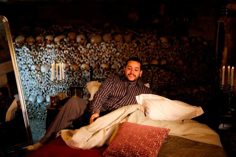 Guest Brazilian Pedro Arruda, 27, poses in the bed prior to spend the Halloween night with his mother Monica in Paris' creepy Catacombs amid skulls and bones, in Paris, France, Saturday, Oct, 31, 2015.