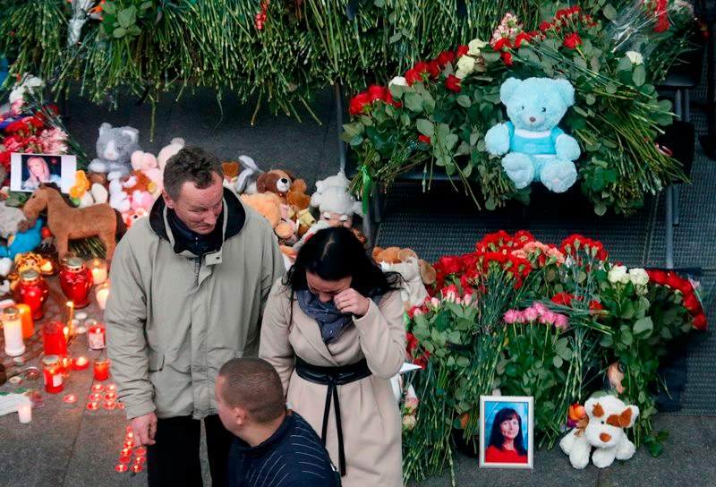 A couple react as they come to lay flowers and toys at an entrance of Pulkovo airport outside St.Petersburg, Russia, during a day of national mourning for the plane crash victims, on Sunday, Nov. 1, 2015.