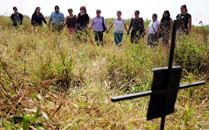 Relatives of missing people hold hands as they stand in an unofficial cemetery that is believed to have been used to bury about 150 bodies of crime victims near the town of Tetelcingo, Mexico, Friday, Nov. 6, 2015. 