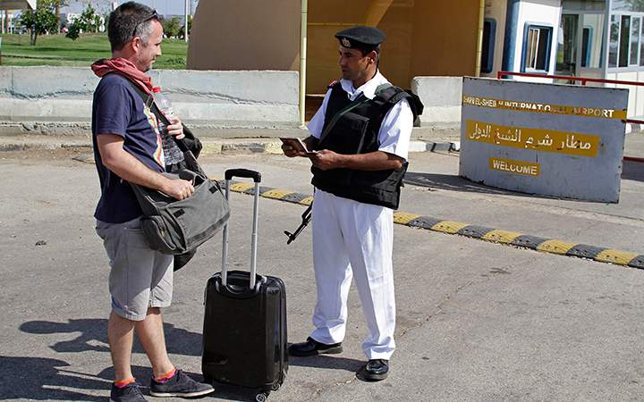 An Egyptian policeman checks a Russian tourist's passport at the main entrance to the Sharm el-Sheikh airport in Egypt on Saturday, Nov. 7, 2015. 