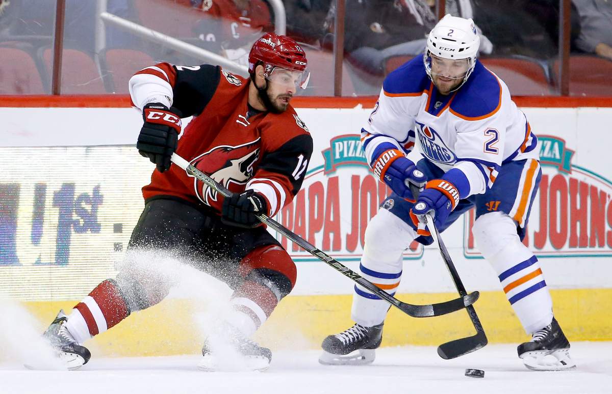Arizona Coyotes' Brad Richardson (12) battles Edmonton Oilers' Andrej Sekera (2), of the Czech Republic, for the puck during the first period of an NHL hockey game Thursday, Nov. 12, 2015, in Glendale, Ariz.