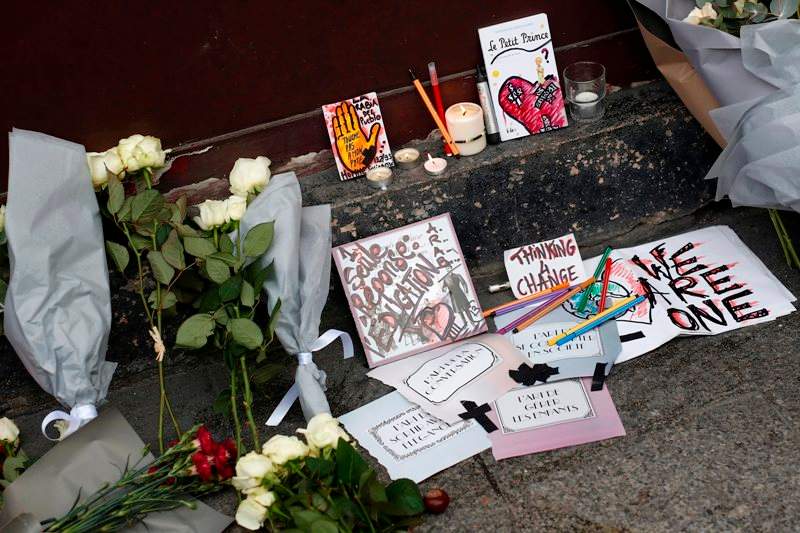 Cards, candles and flowers are placed in front of the Carillon cafe in Paris Saturday Nov. 14, 2015, a day after over 120 people were killed in a series of shooting and explosions.