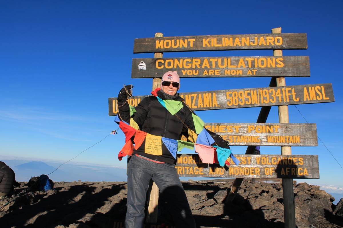 Kate standing at the top of Africa holding the prayer flags containing messages from those who donated to BC Children's Hospital.