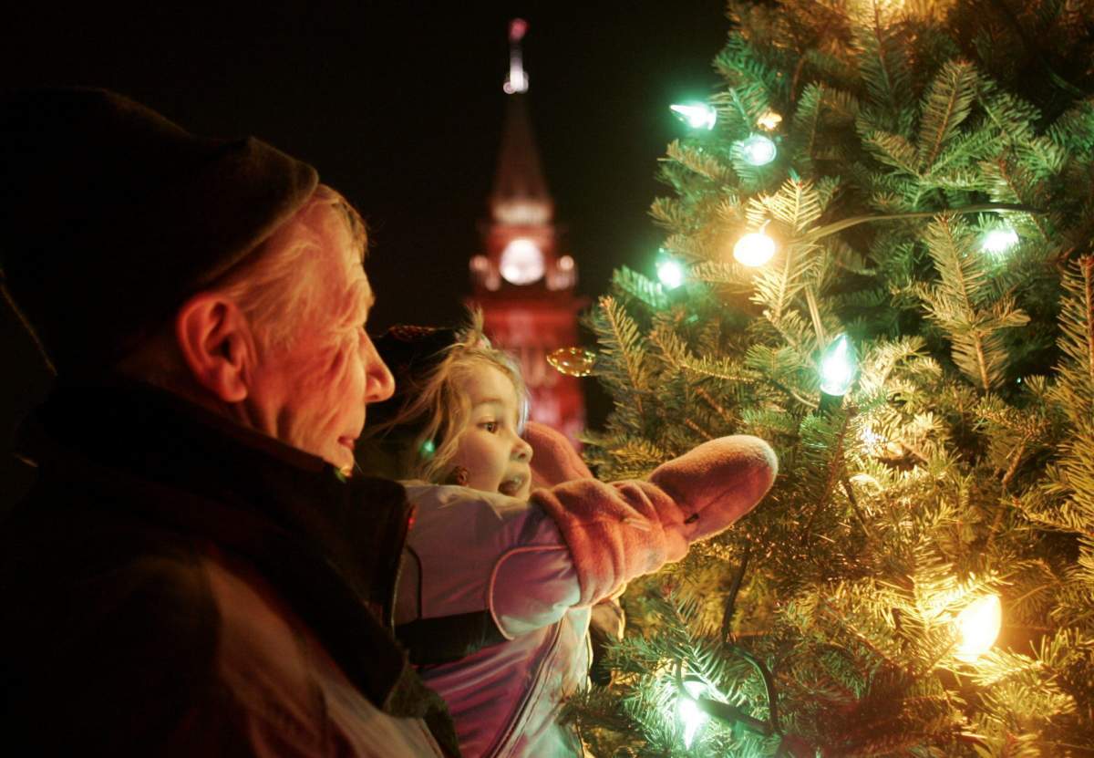 FILE: A child and her grandfather view Christmas lights on a spruce tree. 