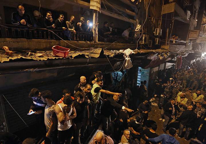 People gather near the site of a twin suicide attack in Burj al-Barajneh, southern Beirut, Lebanon on Thursday, Nov. 12, 2015.