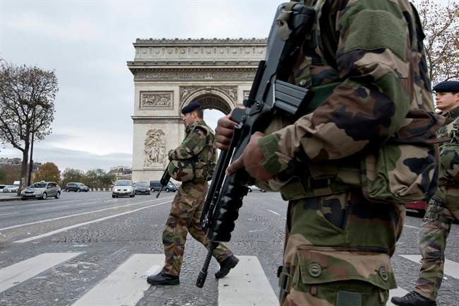 French soldiers cross the Champs Elysees avenue passing the Arc de Triomphe in Paris, Monday, Nov. 16, 2015. 