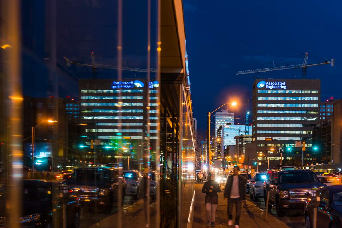A couple walks along Jasper Avenue at night. 