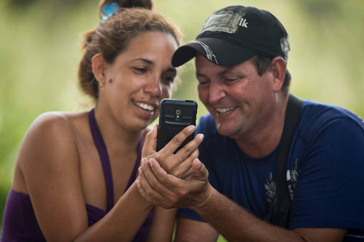 In this Friday, Nov. 20, 2015 photo, Cuban migrants Annieli de los Reyes and Carlos Mena talk with a Annieli's mother back in Cuba, at a shelter in La Cruz, Costa Rica, on the border with Nicaragua. "We have been able to stay in contact with all the persons that are ahead of us and help those behind," the couple said when asked on how technology is helping them on their trip. The local sales office for telecommunications company Movistar has increased the number of sales vans along the border from two to seven, most stationed permanently outside the Cubans' temporary encampments in schools and churches, selling 2-for-1 $3-per-megabyte data packages to a steady stream of Cuban migrants.