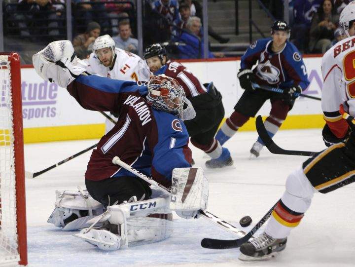 Colorado Avalanche goalie Semyon Varlamov, left, of Russia, deflects a shot off the stick of Calgary Flames center Sam Bennett during the second period of an NHL hockey game Tuesday, Nov. 3, 2015, in Denver.