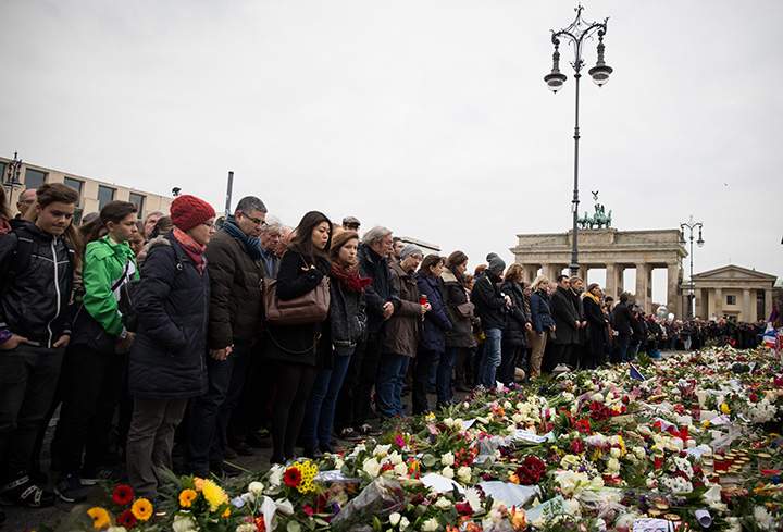 People pause for a minute of silence at the Brandenburg Gate in Berlin on Nov. 16, 2015, to honour the victims of the terrorist attacks in France.