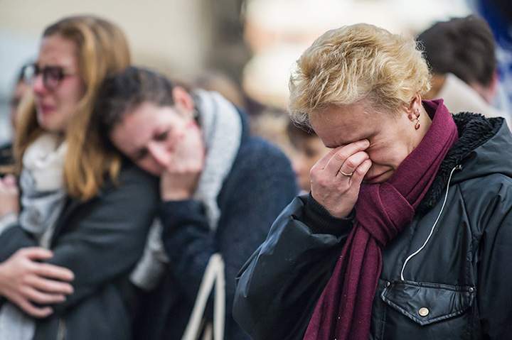 People react, in front of the restaurant Le Carillon, one of the establishments targeted in Friday’s gun and bomb attacks, in Paris, Monday, Nov. 16, 2015.