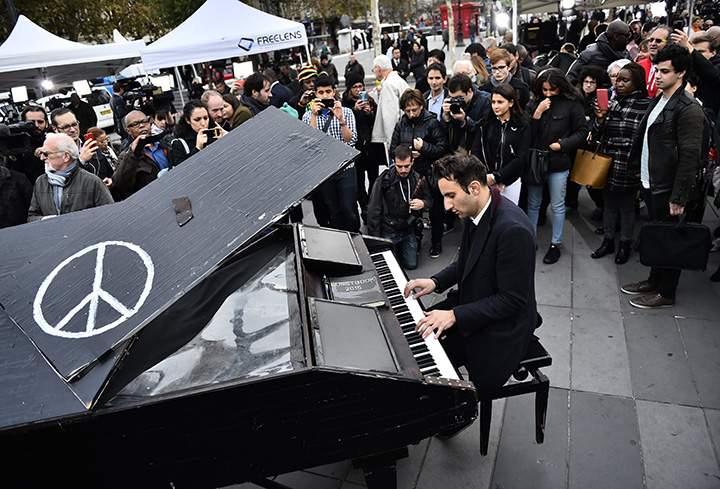 A man plays piano as people gather after observing a minute of silence to pay tribute to victims of the attacks in Paris.