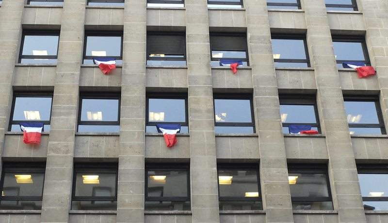 French flags hang from an office building in Paris, Friday, Nov. 27, 2015. French President Francois Hollande called on his compatriots to hang French tricolor flags on Friday to pay homage to the 130 victims of the Nov. 13 attacks.