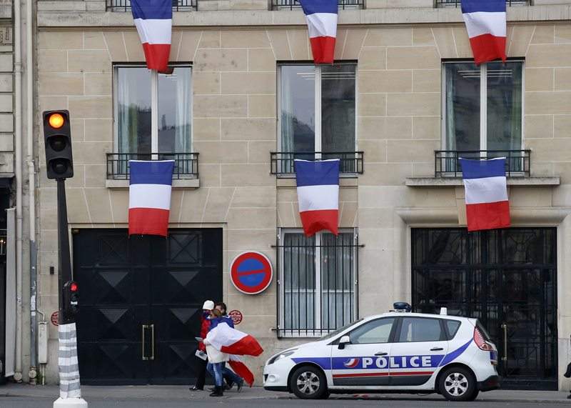 People drapped in the national flag walk past a building decorated with French flags in Paris, Friday, Nov. 27, 2015..