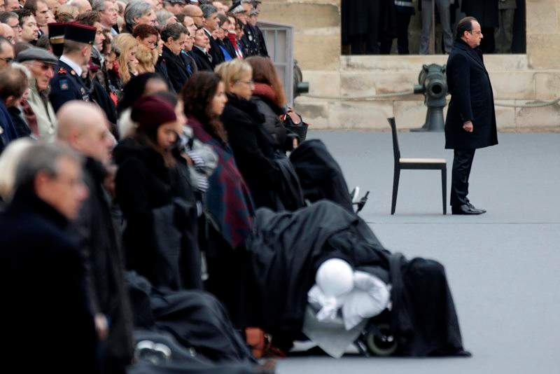 French President Francois Hollande, right, attends a ceremony to honor the 130 victims killed in the Nov. 13 attacks, in the courtyard of the Invalides in Paris, Friday, Nov. 27, 2015.