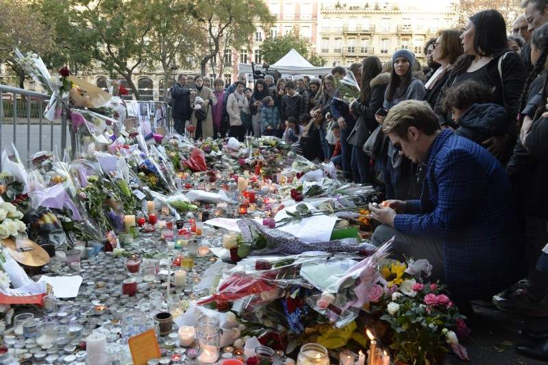 People mourn as they gather at a makeshift memorial near the Bataclan concert hall in Paris on November 15, 2015, two days after a series of deadly attacks