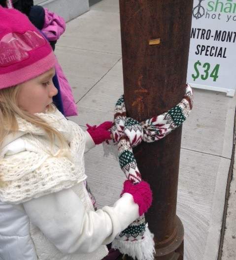 A child wraps a scarf around a pole along Spring Garden Road on Sunday.