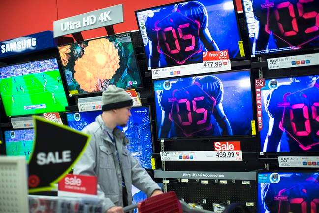 A holiday shopper browses the electronics section against a backdrop of televisions at a Target store Friday.