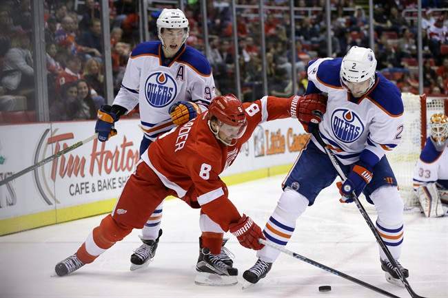 Detroit Red Wings left wing Justin Abdelkader (8) reaches for the puck next to Edmonton Oilers defenseman Andrej Sekera (2) of the Czech Republic during the second period of an NHL hockey game, Friday, Nov. 27, 2015, in Detroit. 