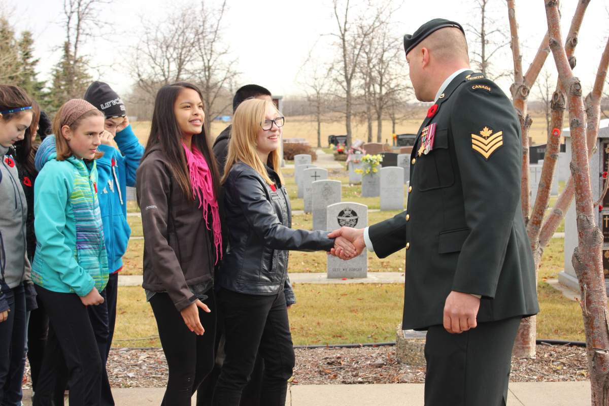 Students attending a No Stone Left Alone ceremony in 2014 shake the hand of a soldier in attendance.