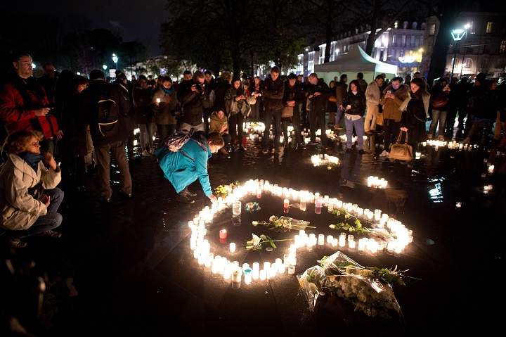 A woman places a candle on November 20, 2015 on the water mirror on the esplanade of the Chateau des Ducs in Nantes, western France, to pay tribute to the victims of the attacks of November 13.