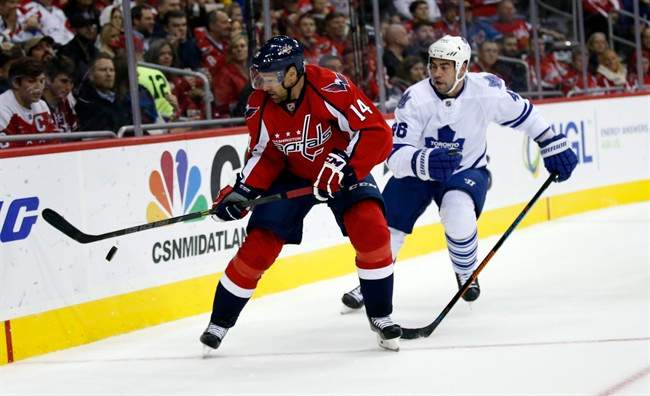 Washington Capitals right wing Justin Williams (14) goes after the puck with Toronto Maple Leafs defenseman Roman Polak (46), from the Czech Republic, in the first period of an NHL hockey game, Saturday, Nov. 7, 2015, in Washington.
