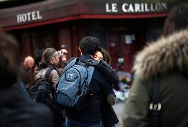 People react in front of the Carillon cafe and the Petit Cambodge restaurant in Paris Saturday Nov. 14, 2015, a day after over 120 people were killed in a series of shooting and explosions. (AP Photo/Jerome Delay)