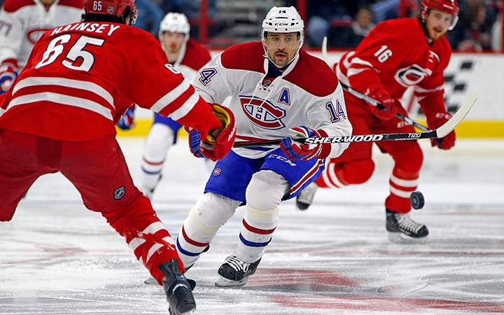 Montreal Canadiens' Tomas Plekanec chips the puck past Carolina Hurricanes' Ron Hainsey during the first period of an NHL hockey game Saturday, Dec. 5, 2015, in Raleigh, N.C. 