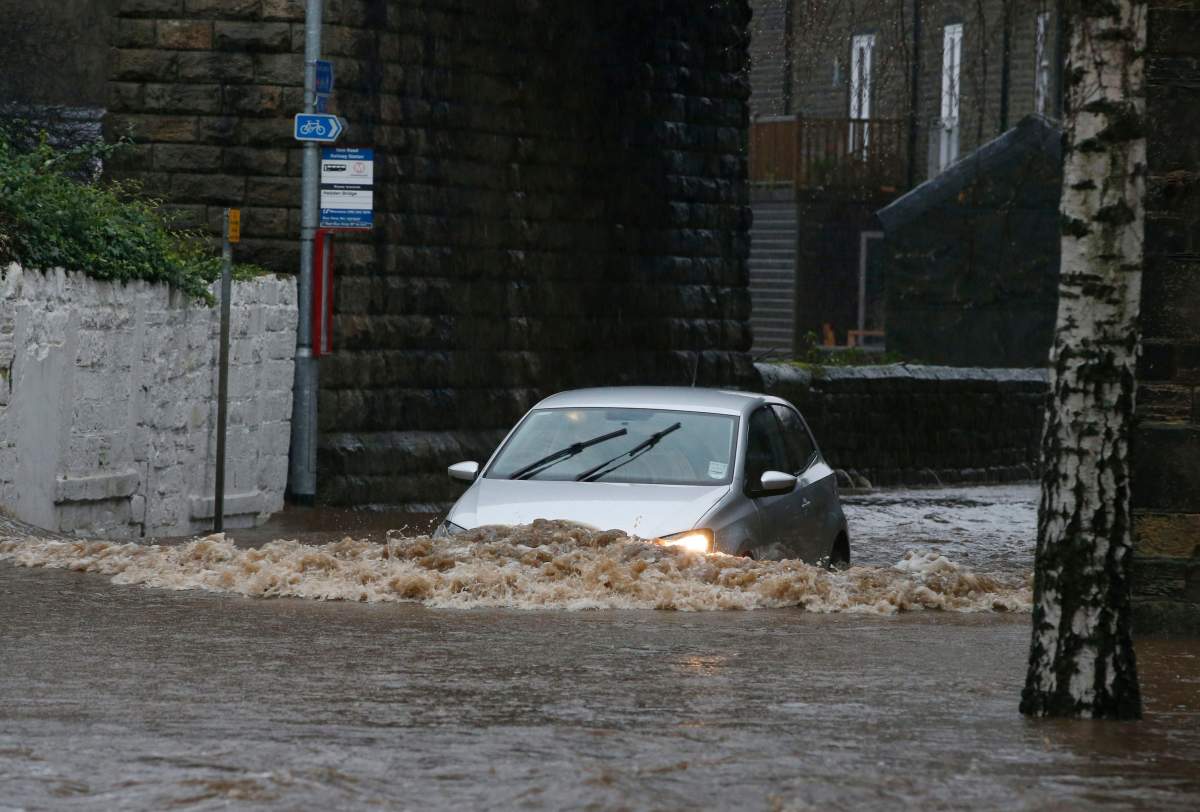 A car drives through flood waters at Mytholmroyd in Calderdale, West Yorkshire, England, Saturday Dec. 26, 2015.