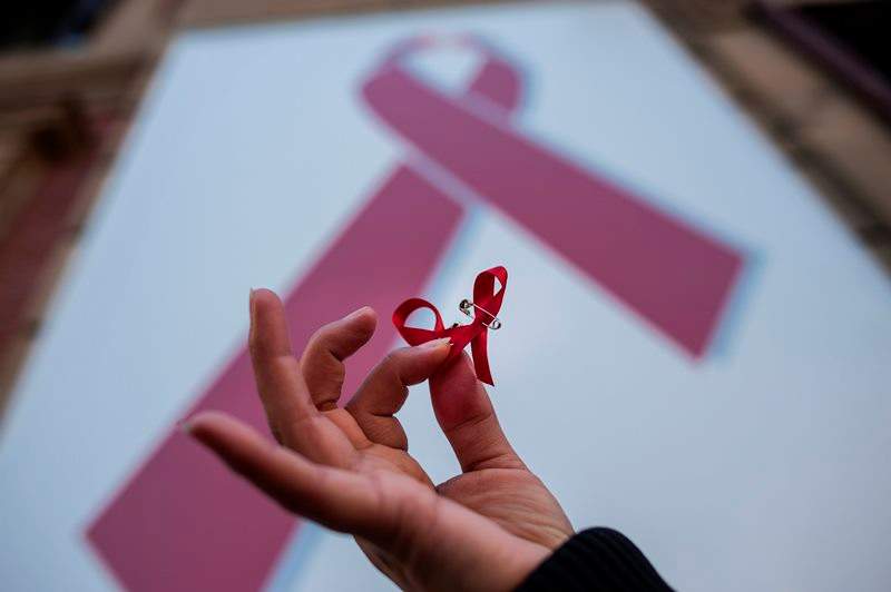 A woman holds a red ribbon symbol of the fight against AIDS during a demonstration on the World Aids Day, in  Spain, Tuesday, Dec. 1, 2015. 