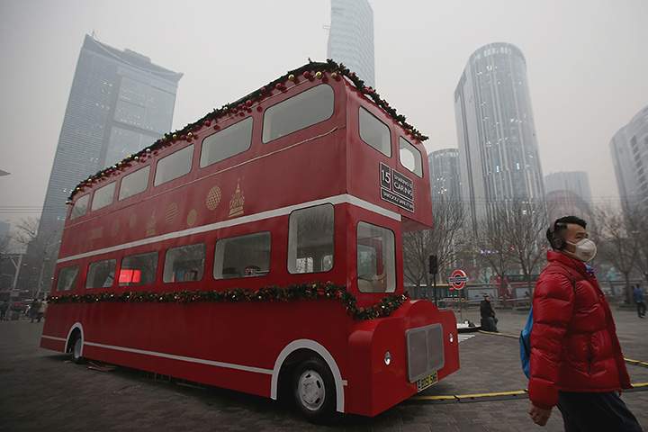 A man wearing a mask passes a double-decker bus model during a day of heavy pollution on December 8, 2015 in Beijing, China.