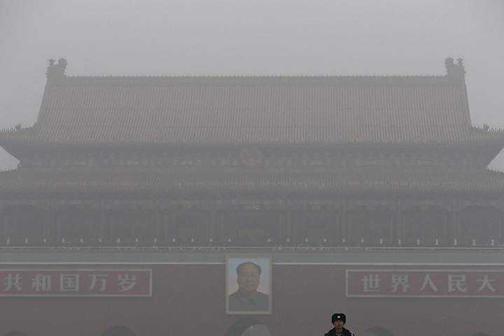 A Chinese paramilitary policeman stands on duty near Tiananmen Gate shrouded with heavy pollution and fog in Beijing, Tuesday, Dec. 1, 2015.
