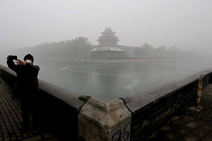 A man wearing a mask to protect himself from pollutants takes a selfie near the Turret of the Forbidden City on a heavily polluted day in Beijing, Tuesday, Dec. 1, 2015.