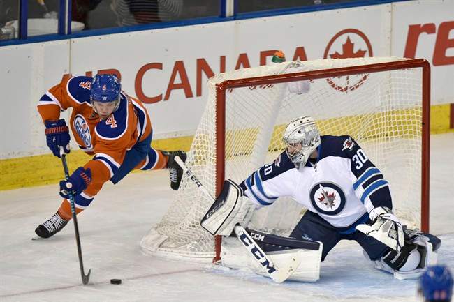 Winnipeg Jets goalie Connor Hellebuyck, covers the net as Edmonton Oilers' Talor Hall controls the puck during first period NHL action in Edmonton, Alta., on Monday, December 21, 2015.