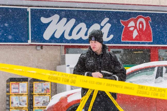 A police member removes crime scene tape at a Mac’s convenience store in Edmonton on Friday, December 18, 2015.