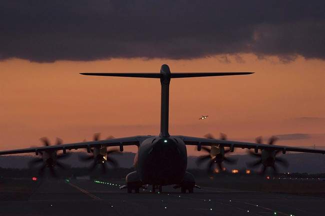 A fighter jet in the background landing as a transport aircraft is seen on the ground at the RAF Akrotiri, a British air base near the coastal city of Limassol, Cyprus, Thursday, Dec. 3, 2015. 