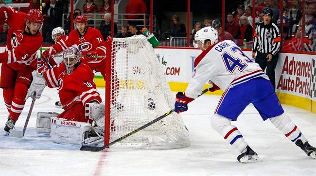 Montreal Canadiens' Daniel Carr (43) wraps the puck around the net to slip it past Carolina Hurricanes goalie Cam Ward (30) with Hurricanes Noah Hanifin (5) nearby during the first period of an NHL hockey game, Saturday, Dec. 5, 2015, in Raleigh, N.C.