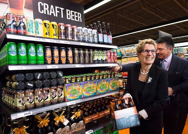 Ontario Premier Kathleen Wynne, left, and Minister of Finance Charles Sousa, right, pick beer at a Loblaws grocery store in Toronto on Tuesday, December 15, 2015.